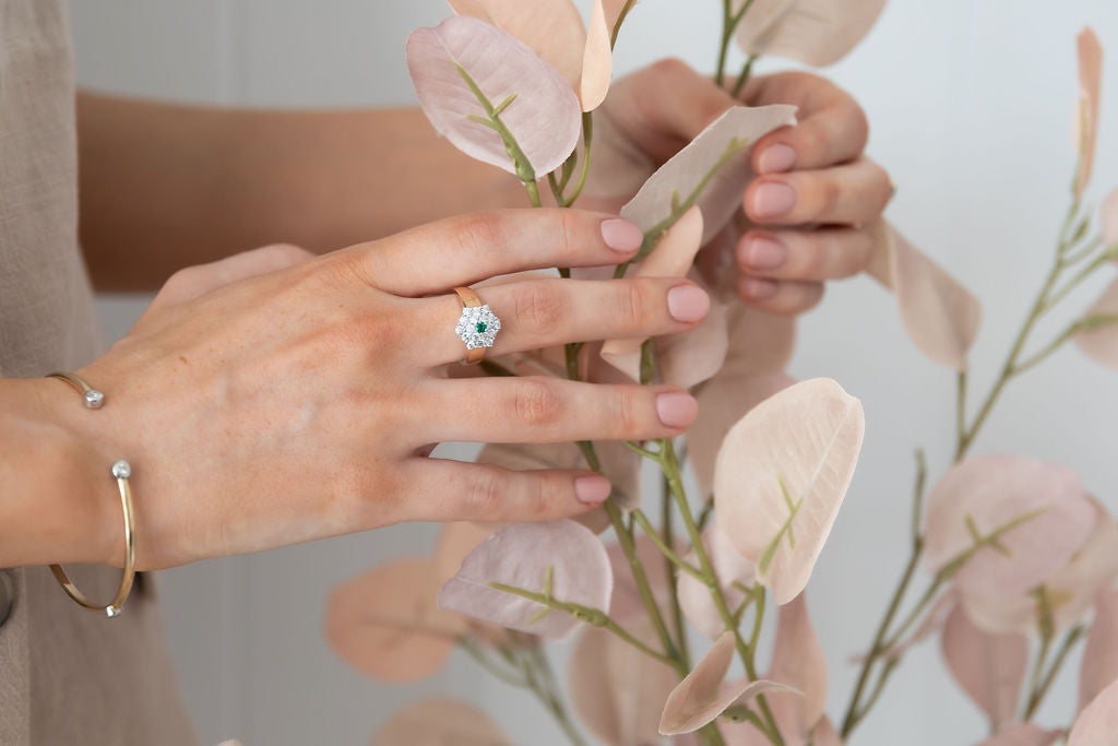 Natural Green Emerald and Diamond Ring Set in Yellow gold Floral Shape on hand holding  peach leaves plant