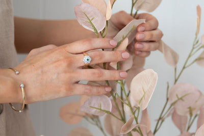 Natural Green Emerald and Diamond Ring Set in Yellow gold Floral Shape on hand holding  peach leaves plant