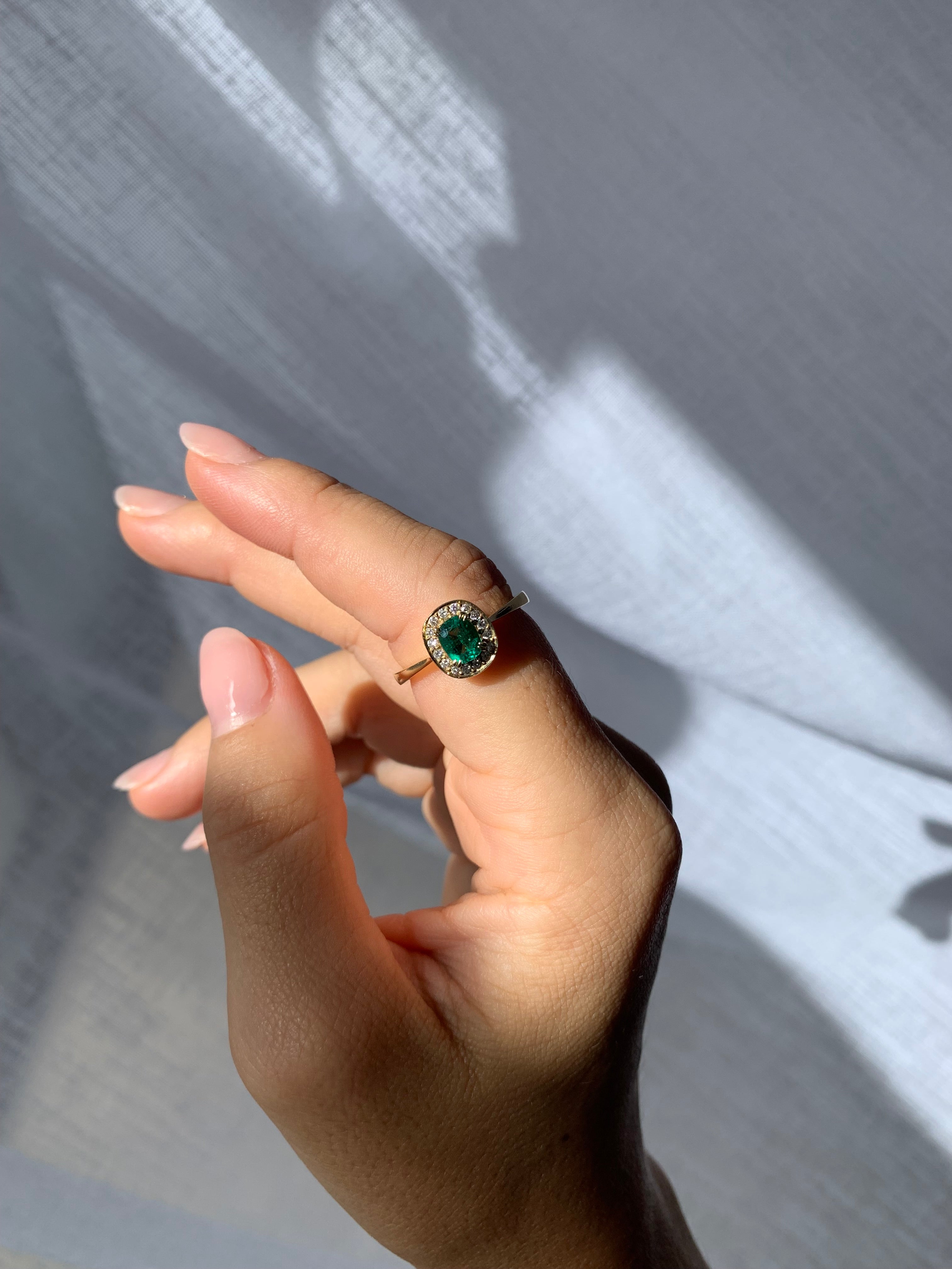Hand wearing a ring with a green gemstone on a textured surface
