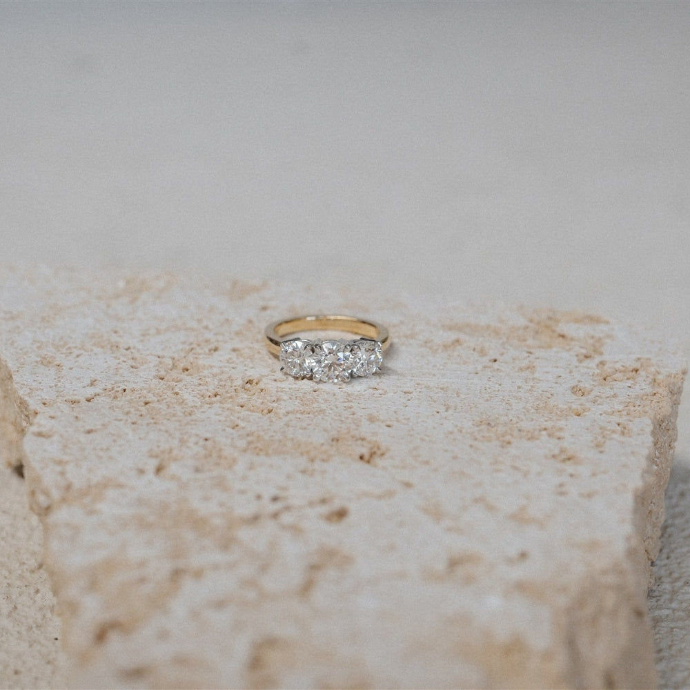 three stone trilogy ring yellow gold platinum on travertine stone